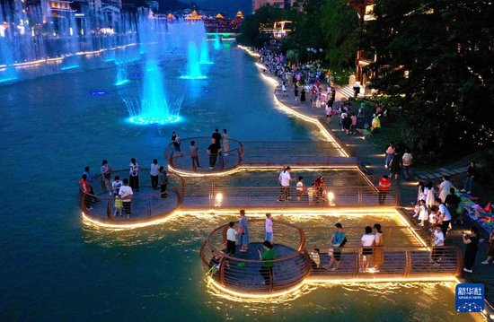 6月10日晚，人们在宣恩县仙山贡水旅游区的贡水河亲水平台上游玩（无人机照片）。