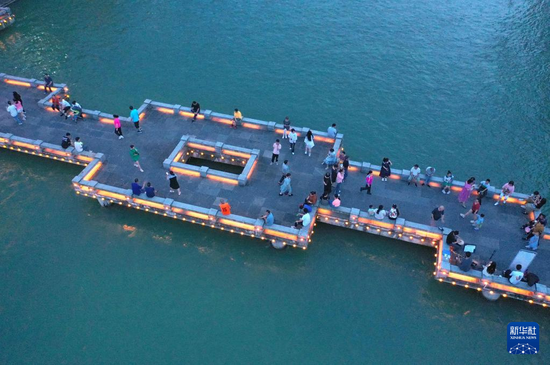 6月10日，人们在宣恩县仙山贡水旅游区的贡水河亲水平台上游玩（无人机照片）。