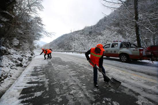 养护工人正在清扫路面残雪