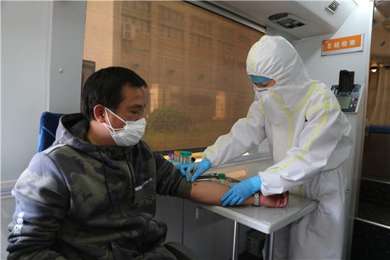 武汉科技大学医院医务人员在移动体检车上进行血常规检查(摄影:张宾)