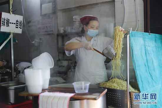 4月22日,在武汉市粮道街的家阳“赵师傅”天天红油热干面店,厨师制作热干面。 新华社记者 沈伯韩 摄
