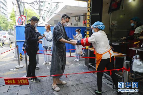 4月22日，市民在武汉市粮道街的家阳“赵师傅”天天红油热干面店购买油饼包烧麦。 新华社记者 沈伯韩 摄