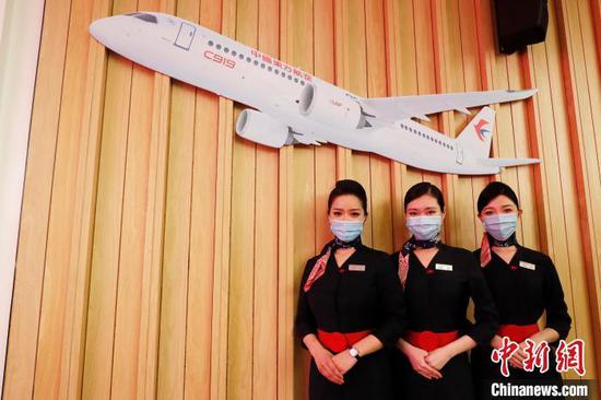 乘務(wù)員在東航C919效果圖下合影留念?！∫罅⑶?攝