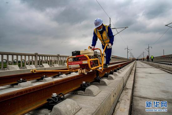 4月8日，中铁十一局三公司建设者在湖北省黄梅县孔垄北站安九高铁铺轨现场紧固轨道扣件。