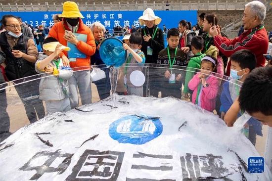 3月26日,小朋友在活动现场放流中华鲟。新华社发(汤德宏 摄)