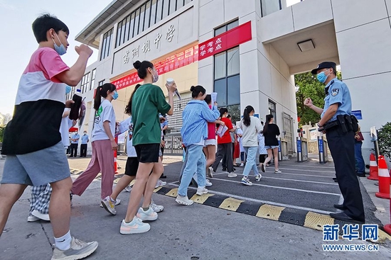 湖北省宜昌市葛洲坝中学考点，现场执勤的公安民警为进入考场的考生们加油鼓劲。新华网发 汪勇 摄