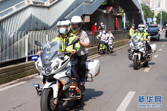 7日，武汉市关山中学考点一名考生忘带身份证向执勤民警求助，东湖高新区交通大队汉警快骑队员包仕俊、沈健驾驶警用摩托车载着考生家长往返40公里，仅用时35分钟及时将身份证送到考点门口。新华网发 周继昌 摄