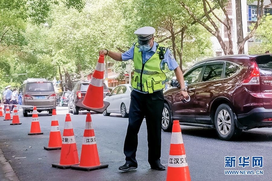 图为武汉市公安局江汉区交通大队二中队民警许毅在武汉市第十二初级中学考点周边摆放锥形桶。新华网发 廖慧 摄