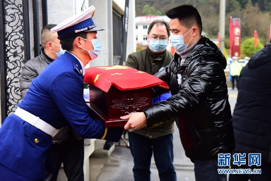 图为1月26日，在湖北省咸丰县烈士陵园，礼兵从工作人员手中接过烈士棺椁。新华网发 李维君摄