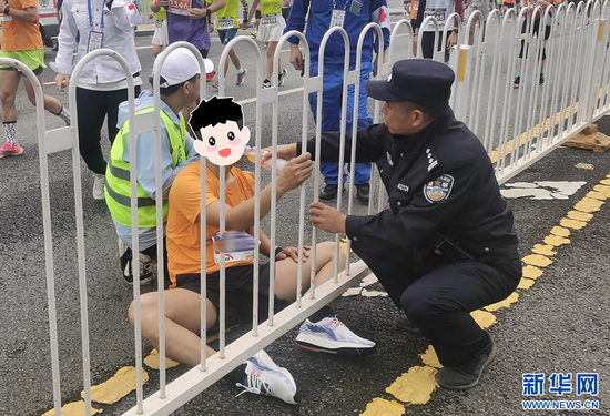 图为执勤民警为体力不支的参赛者补水。新华网发