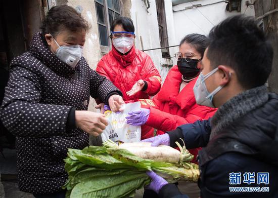 武汉市西城壕社区网格员黄丽芳（左二）与志愿者柳莹（右二）、张琦（右一）为空巢老人送菜（2月7日摄）。新华社记者肖艺九摄