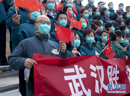 4月15日，北京协和医院国家援鄂抗疫医疗队队员挥舞国旗。当日，北京协和医院国家援鄂抗疫医疗队约180人启程回京。 新华社记者 熊琦 摄