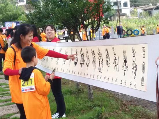 ▲“堂纺叠绣”省级非遗传承人杨钿的“百家姓”作品吸引徒步选手驻足欣赏