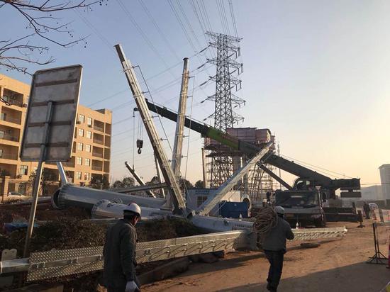 22日,江夏区大桥邢远长街和黄家湖大道交汇处,下线塔正在被缓缓吊起。