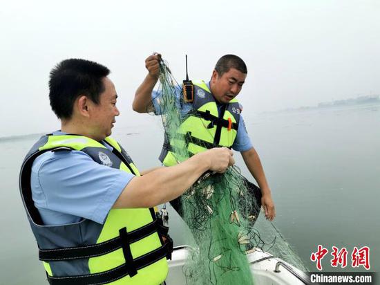 民警正在清理不法分子铺设在汉江中的捕鱼网具　胡传林　摄