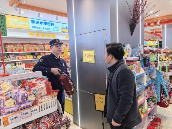 孝感市消防监督员对超市内的灭火器材进行细致检查。孙芳/摄