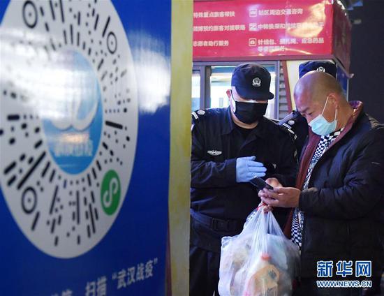 4月8日凌晨，值守在武昌火车站的工作人员协助进站乘客扫描健康码。 新华社记者 李贺 摄