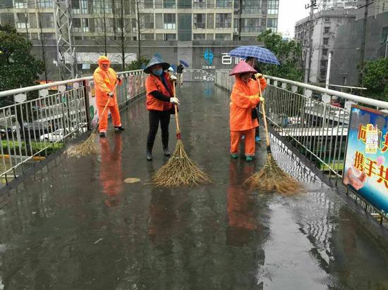 图为:该区城管委城管二所环卫女工正在借雨清洗辖区仁寿路和太平洋两座人行天桥(通讯员 刘顺 摄)