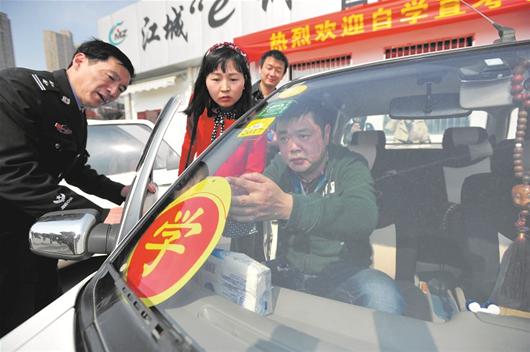 图为：首批领取市民将自学直考学车专用标识贴上车