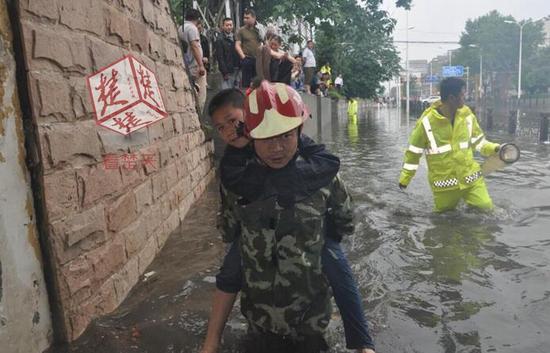 襄阳突降暴雨多处路段积水 消防员背学生老人