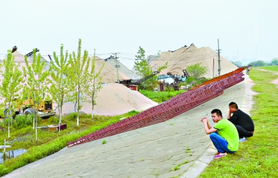 东湖高新区左岭街白浒山整治现场，绿油油的江滩沿线有不少大型沙堆