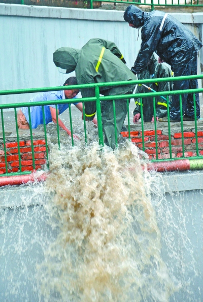 昨天，在武昌晒湖涵洞附近，水务工人冒雨用电钻刨开路边花坛护墙引流渍水，抢时间让公交车恢复通车。记者胡伟鸣摄