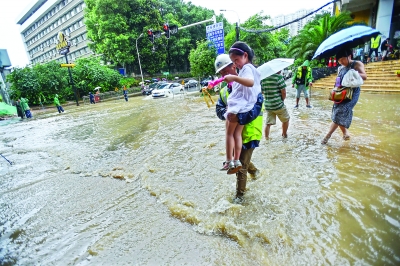 昨日，雄楚大道与珞雄路交叉口积水，武汉市政集团工作人员帮一位妈妈把女儿抱过积水较深的区域
