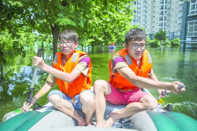渍水导致行路难，郑志远（左）和叶黎鹏两个95后划着橡皮艇，每人差不多送出二十多名居民