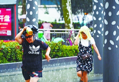 图为青山区建设二路附近两位没带伞的市民在雨中飞奔。记者周迪 摄