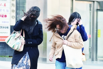 昨日下午突然刮起大风，在武昌街道口，女孩们的长发被大风刮起在风中飞舞，人们顶着大风在路上行走。  记者詹松 摄