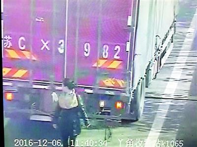 货车高速公路倒车怕被拍 女子下车用身体遮挡