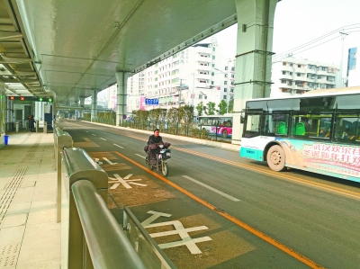 一辆电动车驶过BRT公交站。记者孙笑天 摄