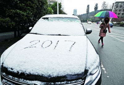 东西湖区临空港大道上，市民从一辆铺满白雪的汽车旁走过。记者史伟 摄