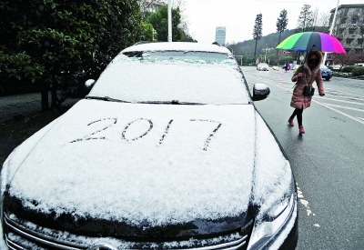 東西湖區(qū)臨空港大道上，市民從一輛鋪滿白雪的汽車旁走過(guò)。記者史偉 攝