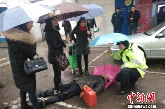 警民为晕倒的老人撑伞挡雨。　王玉桃　摄