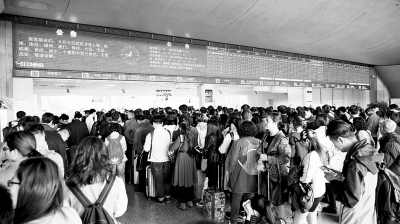 武汉火车站售票大厅内排起长龙，屏幕显示当天由武汉开往上海、杭州等地的车票已售完。     记者何晓刚 摄