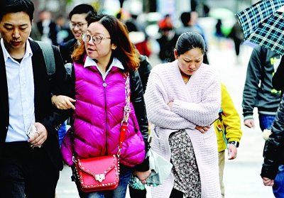 昨天风雨交加，气温陡降，武昌和平大道上，市民重新穿起冬衣御寒。记者苗剑 摄