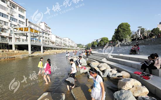 双休日，市民带着孩子在改造后的剑河里戏水玩耍。