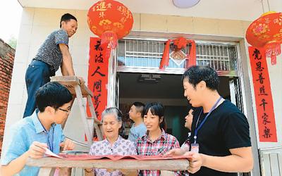 图为9月21日，在福建省宁德市古田县凤埔乡造福工程集中安置点，乡干部黄东华（左一）和喜迁新居的林光锅一家共同贴上喜庆的门联。新华社记者 魏培全摄