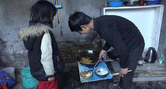 4月3日放学以后，曲比（右）和妹妹自己做晚饭。虽然只有一道菜炒土豆丝，但兄妹俩依旧吃得津津有味。澎湃新闻记者 朱莹 图