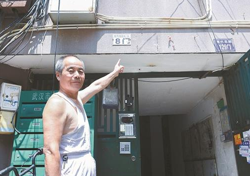 图为居民指着楼栋上的两个门牌号