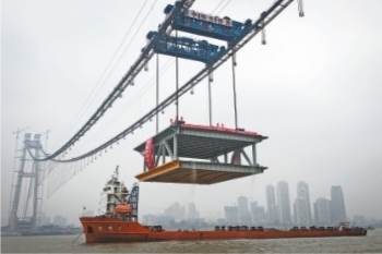 每台吊机起重能力达900吨，两台一起吊起千吨钢梁 记者王谦 摄