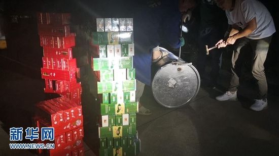 图为5月24日晚,口子大队队员在武深高速赤壁路段对被举报车辆上的油桶进行开桶检查,现场查获卷烟558条。新华网发 王建军摄
