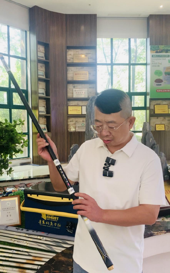 老鬼生物负责人向记者一行讲解鱼竿的商标故事