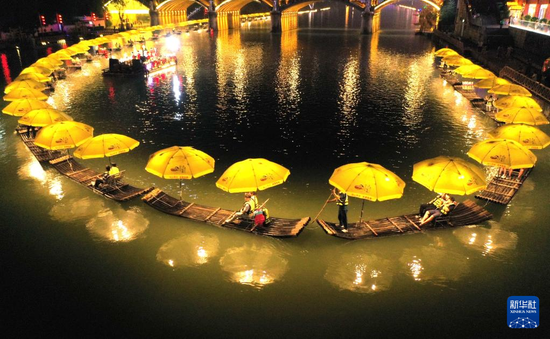 6月10日晚，游客在宣恩县仙山贡水旅游区的贡水河上乘竹筏游玩（无人机照片）。