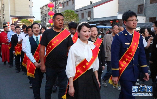 劳模身披红色绶带漫步落雁桥“五一游园会”。新华网发