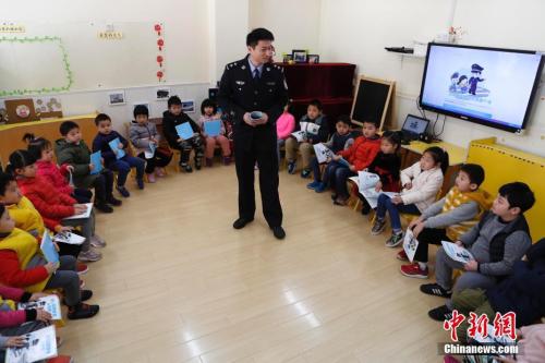 2月23日，上海市中小學(xué)開學(xué)第一天，一套全新的公共安全教育教學(xué)補充讀本被發(fā)放到了全市中小學(xué)和幼兒園。圖為上海市公安局法制總隊一支隊支隊長沈雁輝向幼兒園孩子講解公共安全知識。 中新社記者 殷立勤 攝