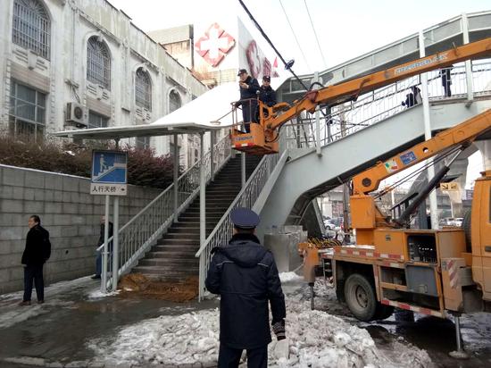 硚口城管执法人员对太平洋跨街人行天桥顶棚积雪和棚檐冰锥进行清理