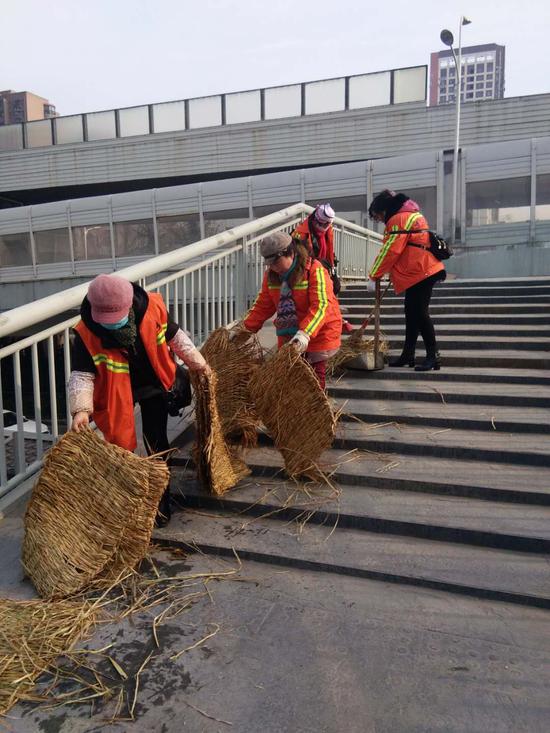 硚口区环卫工人清理利济北路人行天桥台阶上的防滑草垫