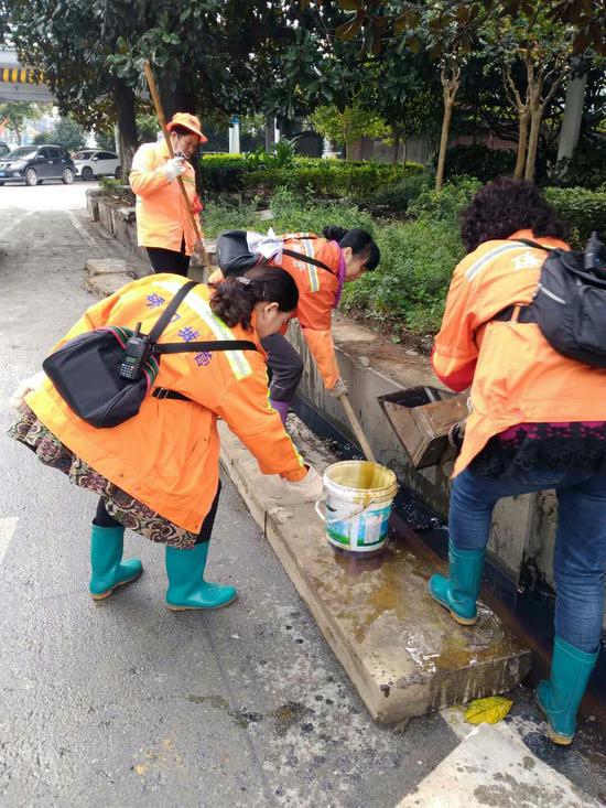 章秋芳和工友们清理路边人字沟淤泥